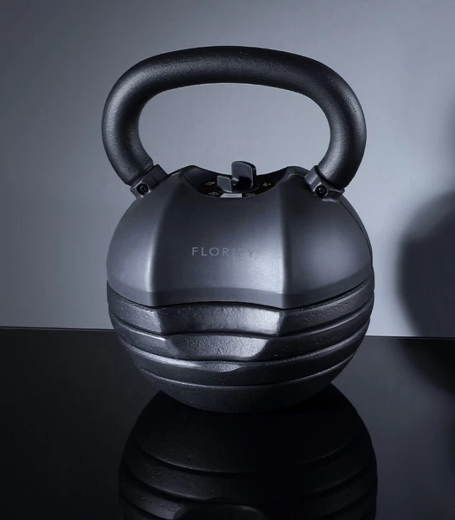 50lb black adjustable kettlebell on a black reflective surface.